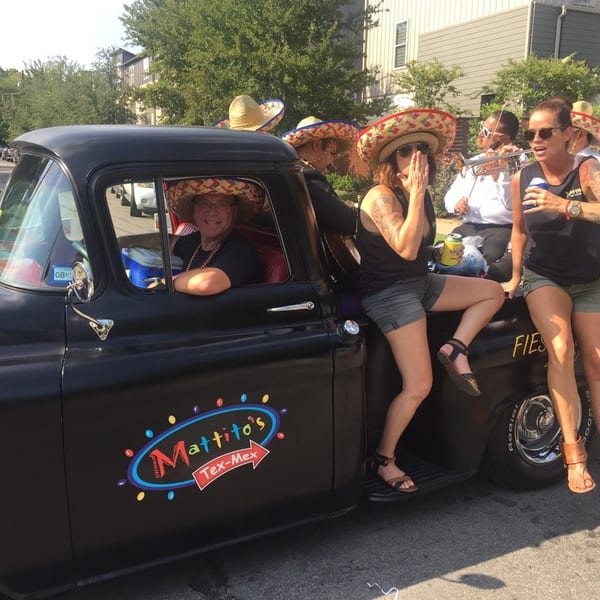 People in sombreros on a black Mattito's Tex-Mex truck, with one person driving and others in the back.