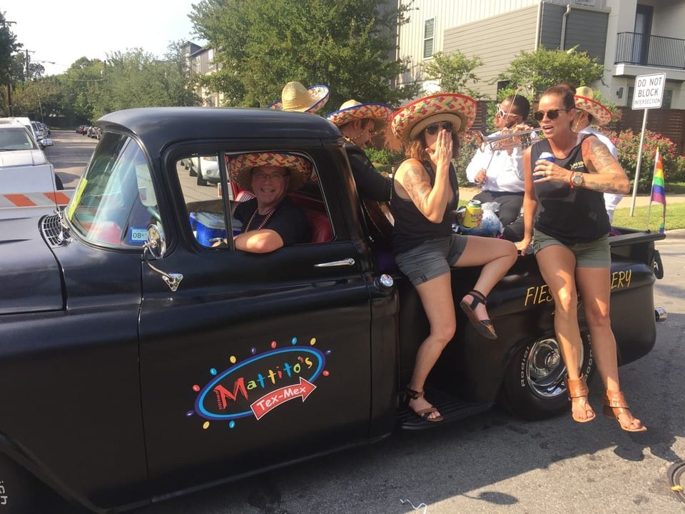 People in sombreros on a black Mattito's Tex-Mex truck, with one person driving and others in the back.