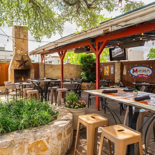 Outdoor patio at Mattito's Tex-Mex with stone fireplace, string lights, and dining tables.