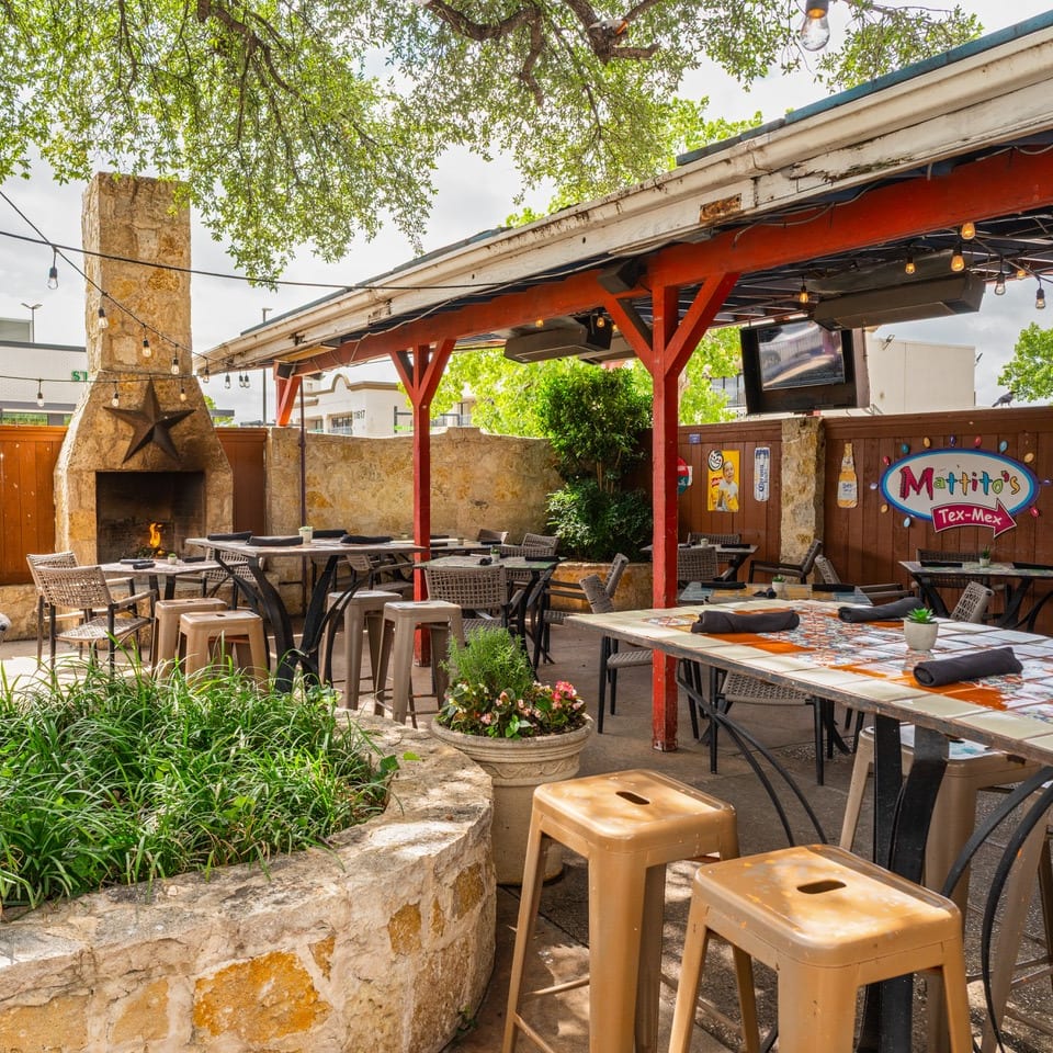 Outdoor patio at Mattito's Tex-Mex with stone fireplace, string lights, and dining tables.