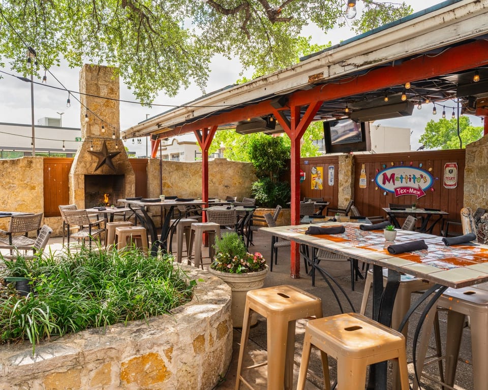 Outdoor patio at Mattito's Tex-Mex with stone fireplace, string lights, and dining tables.