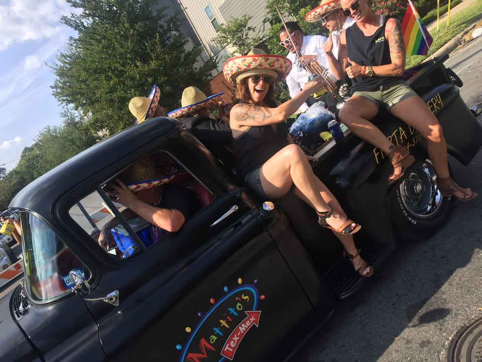 People in sombreros ride in a black Mattito's Tex-Mex truck during a parade.