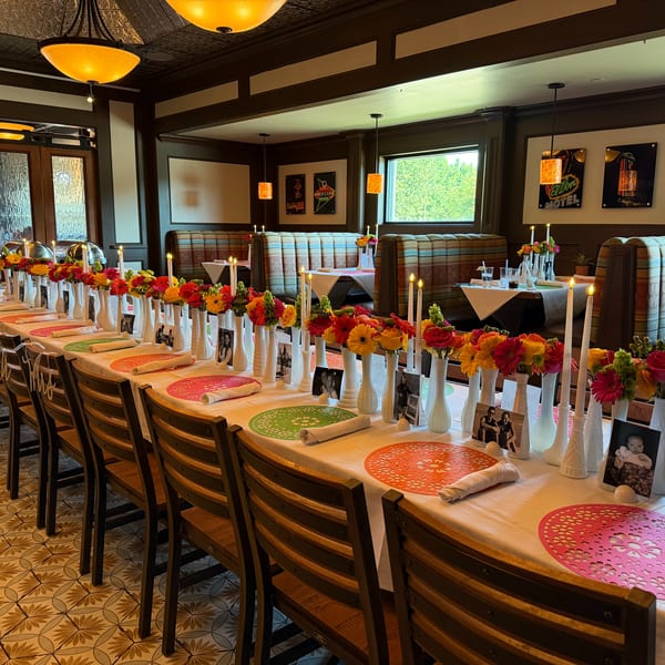Long dining table set with colorful flowers, candles, and place settings in a restaurant.