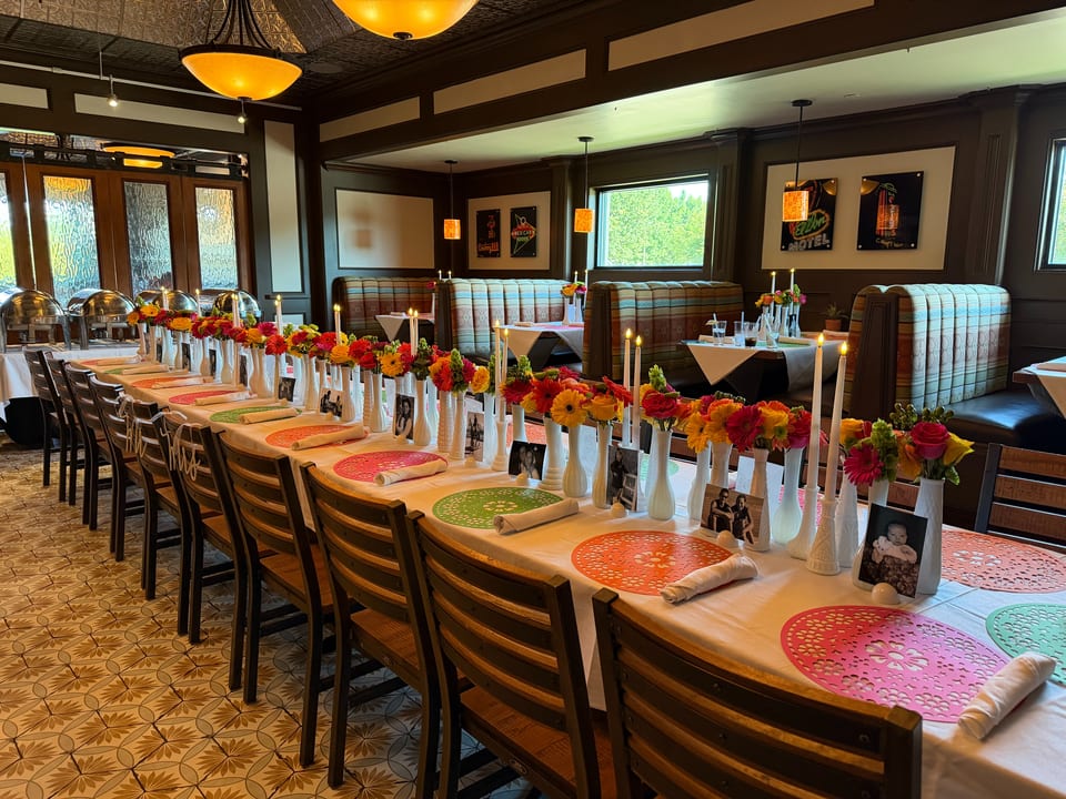 Long dining table set with colorful flowers, candles, and place settings in a restaurant.