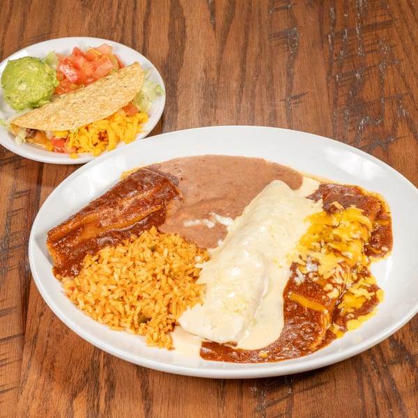 A large plate of Mexican food with rice, beans, a burrito, and an enchilada, plus a taco on a smaller plate.