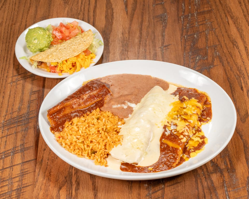 A large plate of Mexican food with rice, beans, a burrito, and an enchilada, plus a taco on a smaller plate.