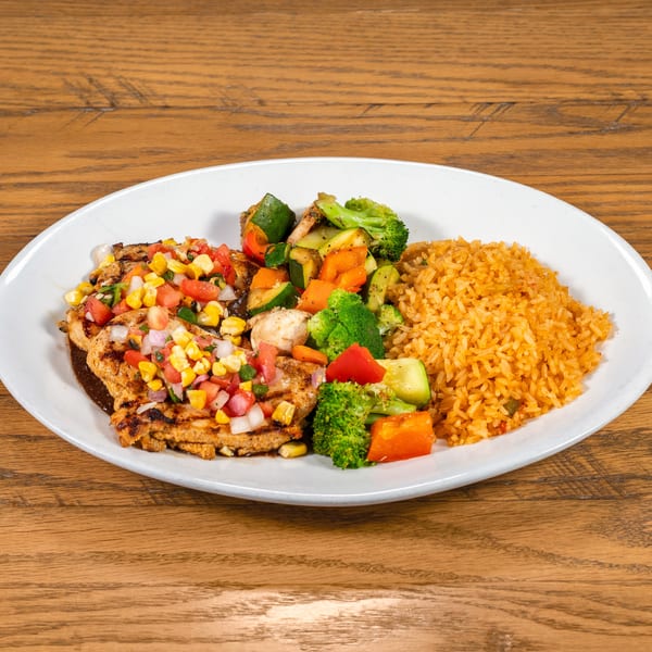 Grilled chicken with corn salsa, mixed vegetables, and Spanish rice on a white plate.