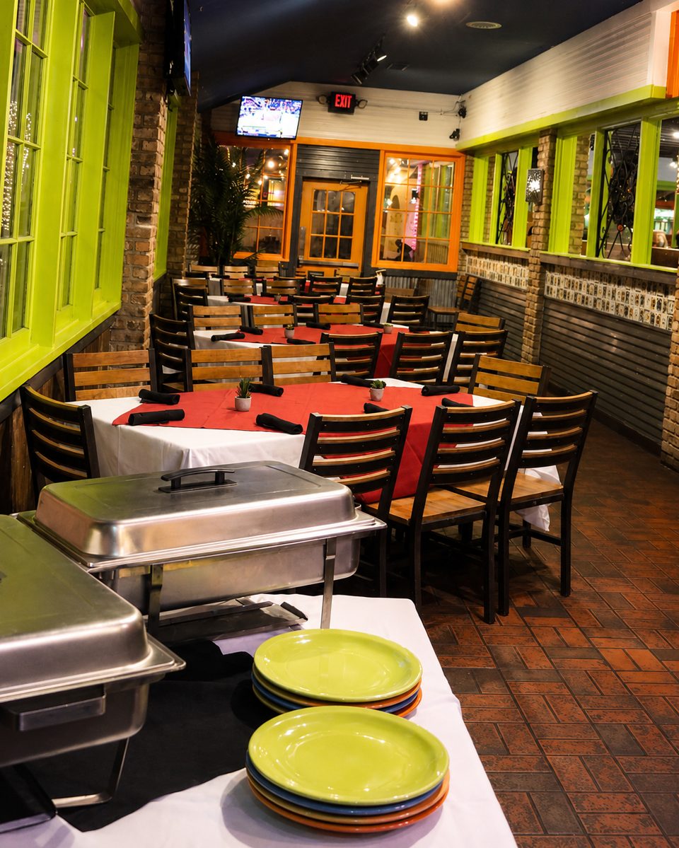 Restaurant dining room with tables set with red tablecloths, buffet chafing dishes, and colorful plates.