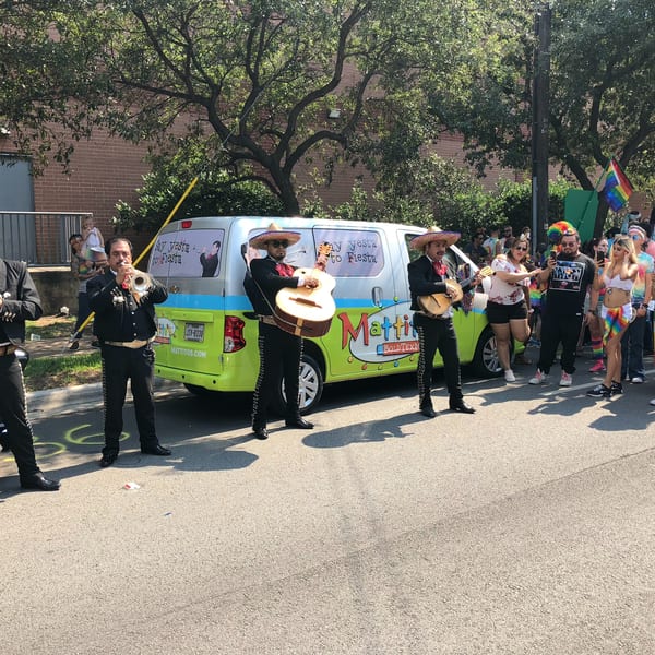 Mariachi band performing in front of a Mattitos van for a crowd of people at a parade.