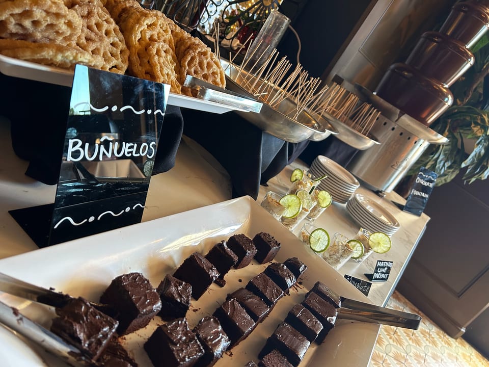 Dessert buffet with buñuelos, chocolate brownies, lime parfaits, and a chocolate fountain.